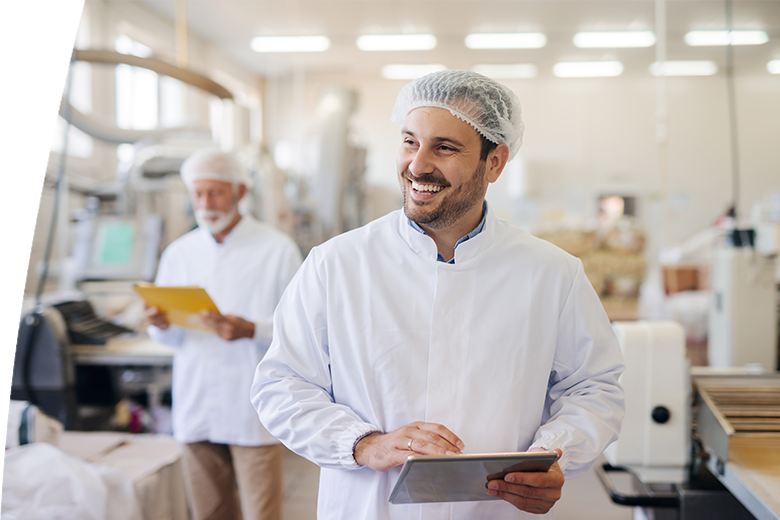 Smiling man using tablet while standing in food factory.